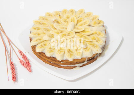 Banana torta biscotto su uno sfondo bianco. Torta dolce con latte condensato salsa. Prodotti da forno Foto Stock