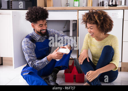 Plumber guardando i danni della tubazione del dissipatore Foto Stock