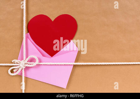 Regalo di San Valentino con cuore rosso card o tag regalo, marrone confezione di carta pacco sfondo, spazio di copia Foto Stock