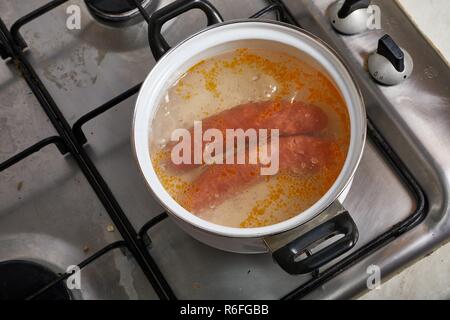 Salsicce di ebollizione sulla stufa Foto Stock