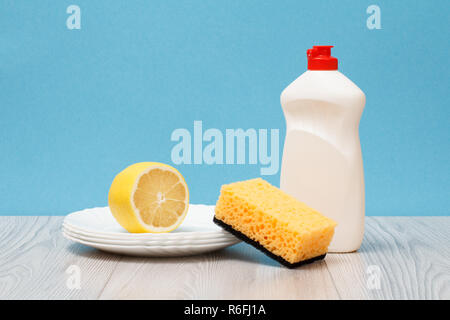 Bottiglia di plastica di detersivo liquido per stoviglie, pulire le piastre, limone e spugna su sfondo blu. Il lavaggio e la pulizia di concetto. Foto Stock