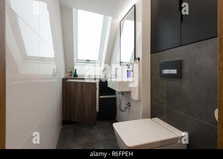 Interno di un piccolo bagno con wc in ceramica su pareti bianche in appartamento  vicino al cestino di rattan Foto stock - Alamy