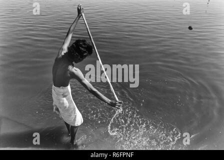 Uomo lavaggio abiti in fiume, India, vecchia annata 1900s foto Foto Stock