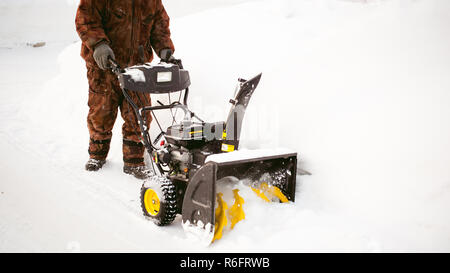 Uomo di funzionamento del ventilatore di neve per rimuovere la neve sul viale di accesso Foto Stock