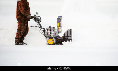 Uomo di funzionamento del ventilatore di neve per rimuovere la neve sul viale di accesso Foto Stock