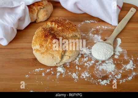 Pane appena sfornato il pane fatto in casa con farina bianca sul tagliere di legno ad alto angolo di visione con spazio di copia Foto Stock