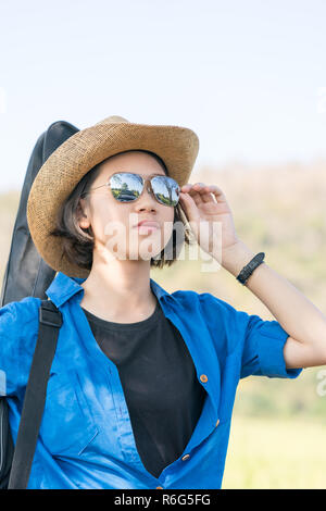 Donna usura hat camminare e portare la sua borsa per chitarra Foto Stock