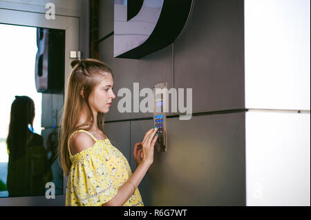 La donna compone un codice appartamento su un sistema elettronico di pannello doorphone Foto Stock