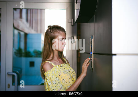 La donna compone un codice appartamento su un sistema elettronico di pannello doorphone Foto Stock