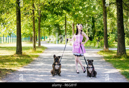 Giovani Pin'Up dalla parte anteriore, tenendo due cani al guinzaglio Foto Stock