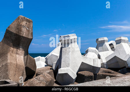 Calcestruzzo ruvido blocchi frangiflutti sono sotto il cielo nuvoloso. Background Industriale foto Foto Stock