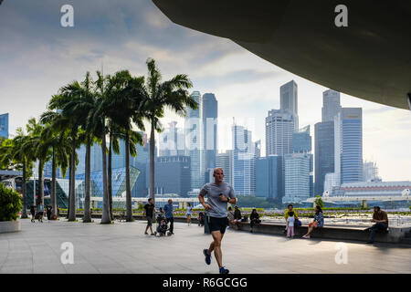 Un uomo fa avanzare attraverso il paesaggio urbano di Marina Bay a Singapore Foto Stock