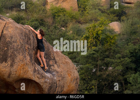 Una femmina di scalatore pratiche la sua arrampicata boulder competenze, Hampi, India. Foto Stock