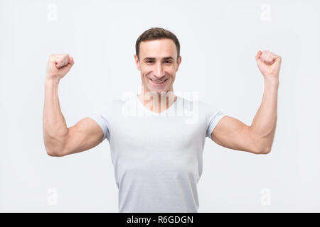 Felice gioiosa uomo forte clenches pugni, vestito in camicia casual Foto Stock