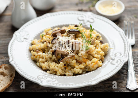 Orzo perlato risotto ai funghi su un tavolo di legno, primo piano, il fuoco selettivo Foto Stock