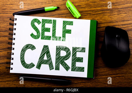 Annuncio della scrittura testo che mostra Self Care. Il concetto di business per prendere la cura per la propria salute scritto sul libro dei notebook nota la carta sullo sfondo di legno. Parola verde lettere. Accanto al mouse. Foto Stock