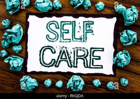 Annuncio della scrittura testo che mostra Self Care. Il concetto di business per prendere la cura per la propria salute scritto su una nota adesiva carta, sullo sfondo di legno con piegata la carta blu significato pensare Foto Stock