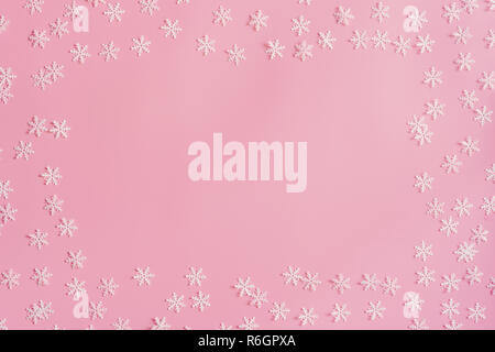 Vista dall'alto il Natale snowflake telaio di frontiera su sfondo rosa. Xmas minimal texture con copia spazio. Foto Stock