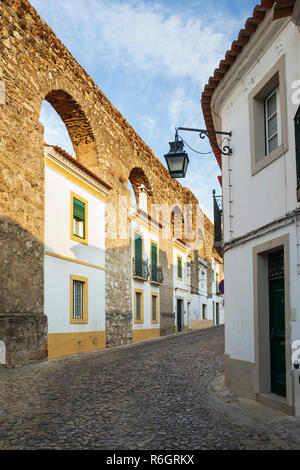 Le sue case dipinte di bianco costruito nel vecchio acquedotto, Evora, Alentejo, Portogallo, Europa Foto Stock