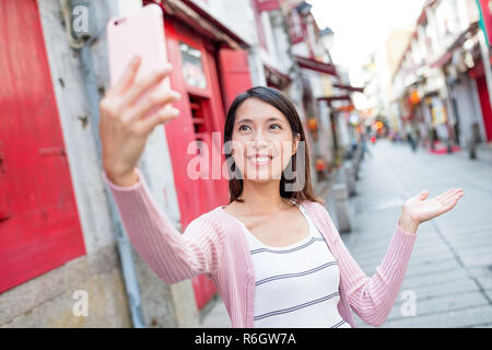 Donna prendendo selfie con telefono cellulare in Rua da Felicidade di Macao Foto Stock