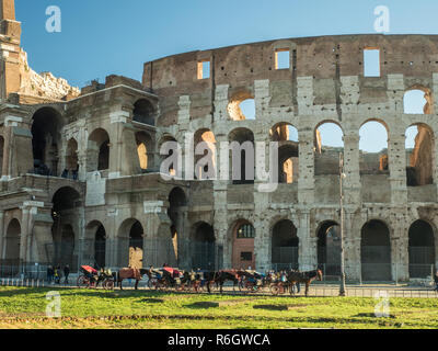 Il Colosseo a Roma, Lazio, Italia. Cavalli con carrozze attendono di portare i turisti in un tour della città. Foto Stock