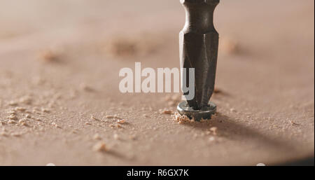 Artigiano aziona la vite nella tavola di legno Foto Stock
