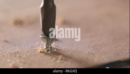 Artigiano aziona la vite nella tavola di legno Foto Stock