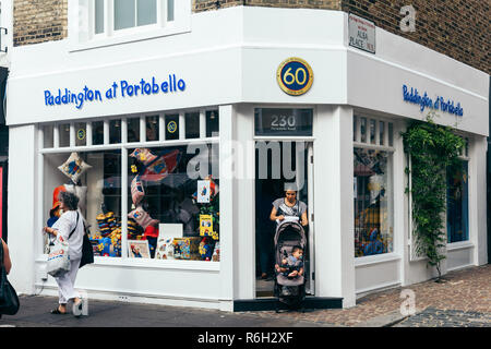 Londra/UK - 20 Luglio 2018: Madre con il suo bambino in un passeggino andando fuori del 'Paddington a Portobello' negozio di giocattoli su Portobello Road, London, Regno Unito Foto Stock