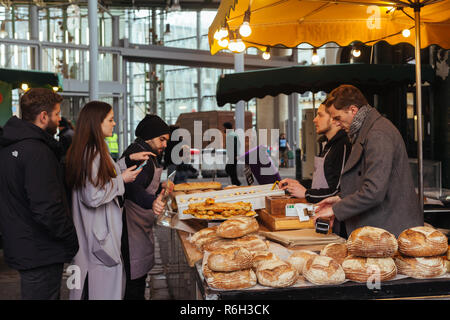 Londra/UK - 25 Marzo 2018: Donna scelta di pane sul mercato di Camden a Londra, Regno Unito Foto Stock