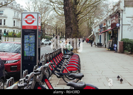 London, Regno Unito - 11 Marzo 2018: il papà con bambini vicino a Santander cicli docking station sul Holland Park Avenue, vicino Princedale Road Foto Stock