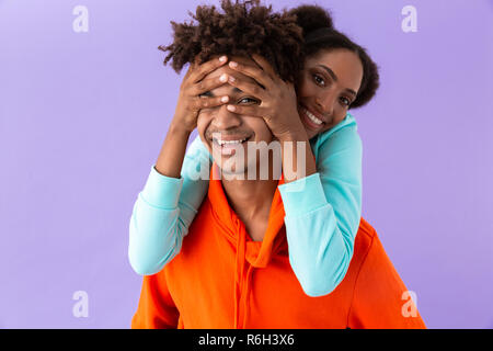 Foto di entusiasti african american fratello piggybacking la gioia della sua sorella isolate su sfondo viola Foto Stock