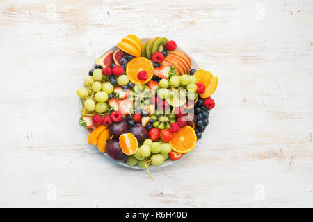 Una sana frutta, fragole lamponi arance Prugne Mele Kiwi uve mirtilli sul bianco tavolo in legno, vista dall'alto Foto Stock