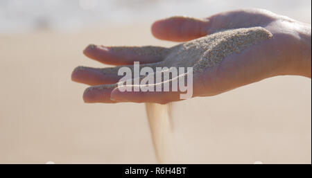 Sabbia di mare in esecuzione attraverso una donna le mani Foto Stock