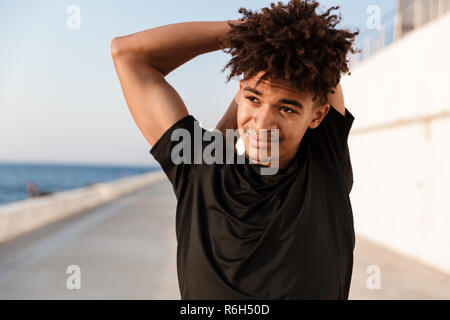 Immagine del bel giovane ragazzo sportivo a fare esercizi all'aperto sulla spiaggia. Foto Stock