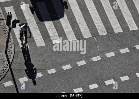 Alta angolazione del ciclista e shadow forma di auto in attraversamento pedonale, Copenhagen, Danimarca e Scandinavia Foto Stock