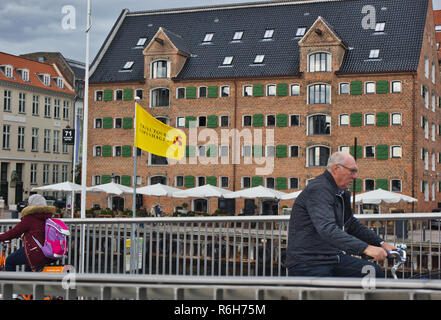 I ciclisti su Inderhavnsbroen (Inner Harbour Bridge) con una conservata Nyhavn warehouse in background, Nyhavn, Copenhagen, Danimarca e Scandinavia Foto Stock