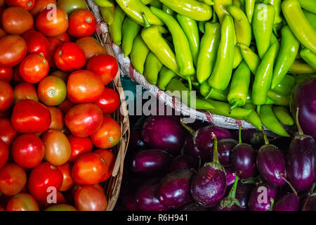 Un colorato display di grandi dimensioni di vegtables freschi compresi i pomodori, peperoncini verdi, e baby melanzane. Foto Stock
