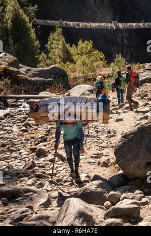 Il Nepal, Jorsale (Thumbug), porter portano carichi pesanti a Namche Bazar lungo il percorso accanto Dudh Khosi river Foto Stock