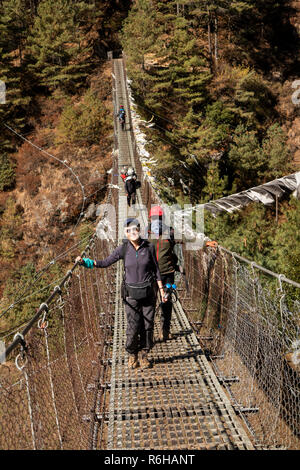 Il Nepal, Jorsale (Thumbug), senior trekker e guida sherpa attraversando la sospensione in metallo ponte sul Dudh Khosi Foto Stock