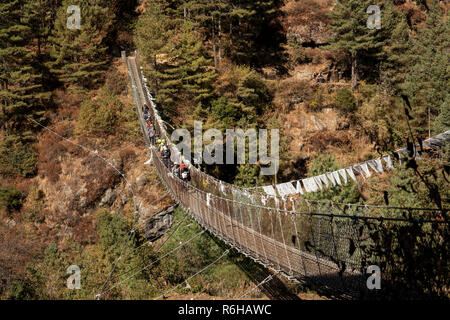 Il Nepal, Jorsale (Thumbug), linea di trekkers occidentale attraversando la sospensione in metallo ponte sul Dudh Khosi river Foto Stock