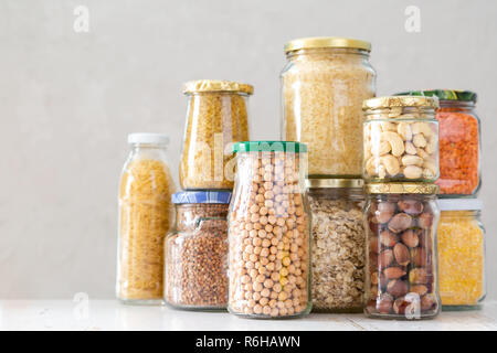 Vari cereali non cotte, cereali, fagioli e pasta per una cucina più sana in vasetti di vetro Foto Stock