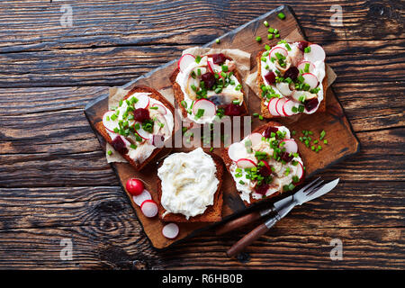 Smorrebrod - danese di fronte aperto sandwich di pane di segale, sgombro affumicato a fette, crema di latte mescolato con rafano grattugiato, barbabietole, rafano fresco, cipolla o Foto Stock