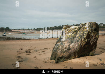 Big Rock in Bretagna beach, ha rivelato a bassa marea con barche posa sul fondo del mare in lontananza, Francia Foto Stock