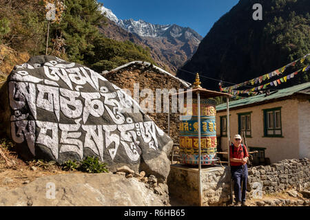 Il Nepal, Benkar, grande buddista intagliato mani la pietra e la preghiera ruota in ingresso al villaggio Foto Stock