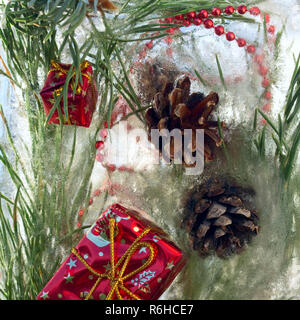 Sfondo rosso di perle e craft regalo di Natale , cono, ramoscello di pino in cubetti di ghiaccio con bolle di aria.Felice anno nuovo 2019 greeting card . Co Foto Stock