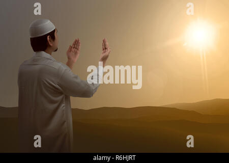 Vista posteriore dei musulmani asiatici alzando la mano e pregando Foto Stock