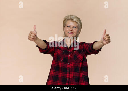 Awe donna con bel sorriso e pollice su gesto in posa contro sfondo colorato Foto Stock