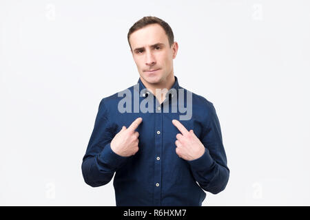 Giovane uomo europeo in completo rivolto a se stesso, trovare scuse o verbalmente la difesa Foto Stock