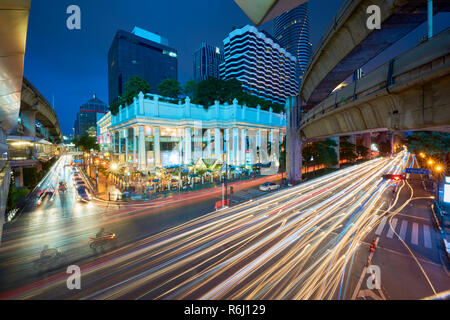 Creative elevato angolo night shot di Ratchaprasong intersezione e Santuario di Erawan a Bangkok, Thailandia, con la luce colorata sentiero da Cars driving passato Foto Stock