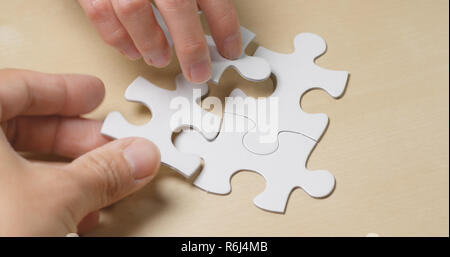 Il lavoro di squadra completando puzzle bianco Foto Stock